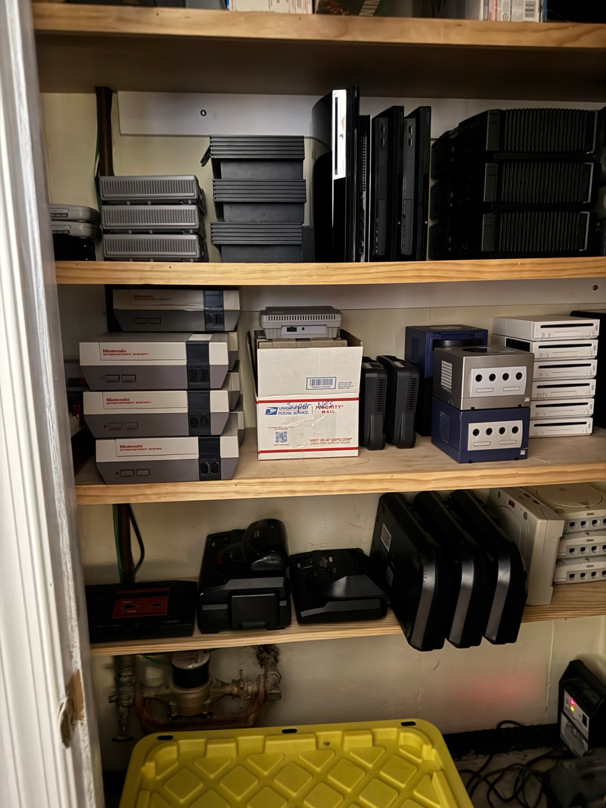 Closet shelves stacked with game consoles