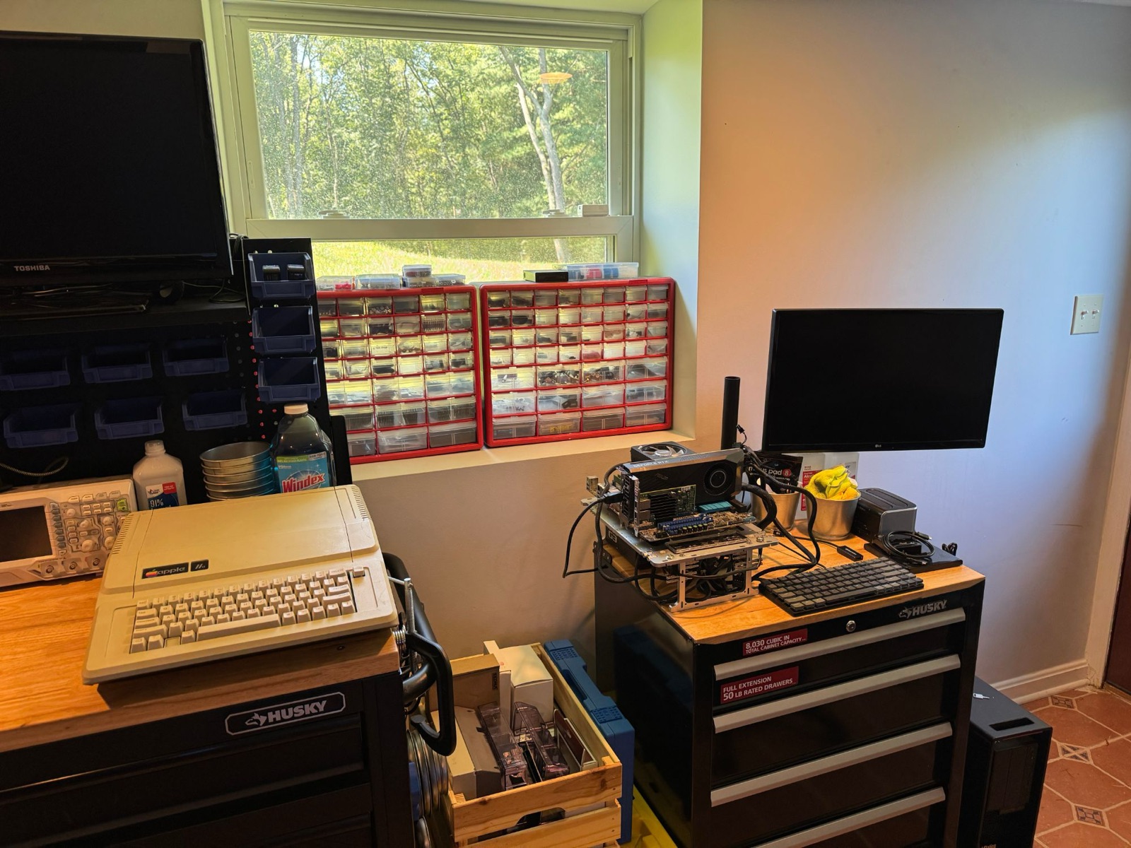 Electronics workbench with parts organizers, an Apple IIe, and an open-frame test bench