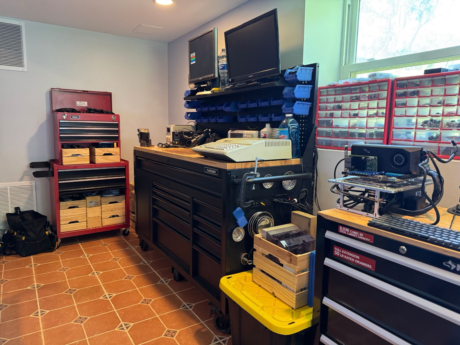 Workshop overview: workbench with pegboard bin storage, parts organizers, and an open-frame hardware test bench